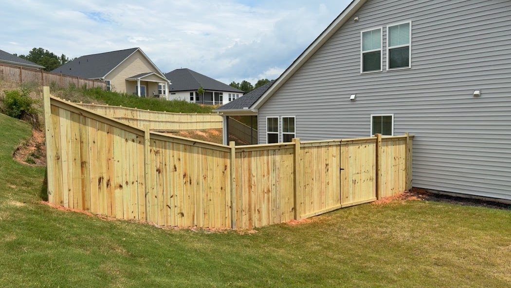 Wood privacy fence wrapping a sloped backyard corner