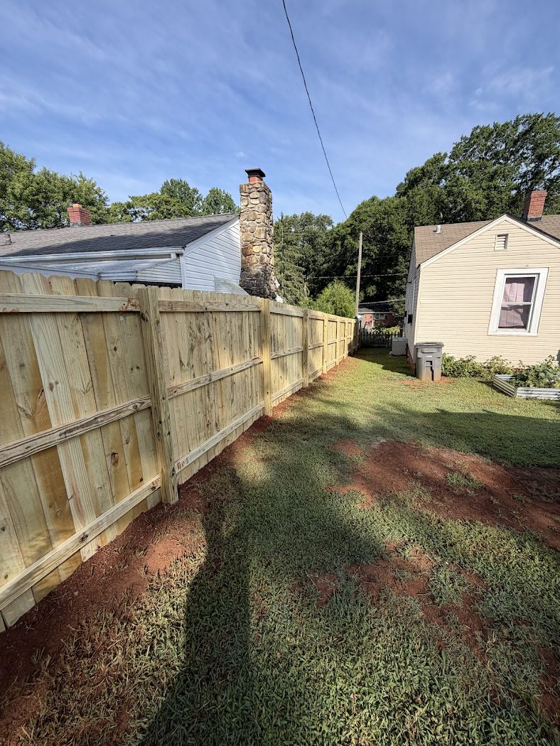 New wood privacy fence enclosing a backyard between two homes